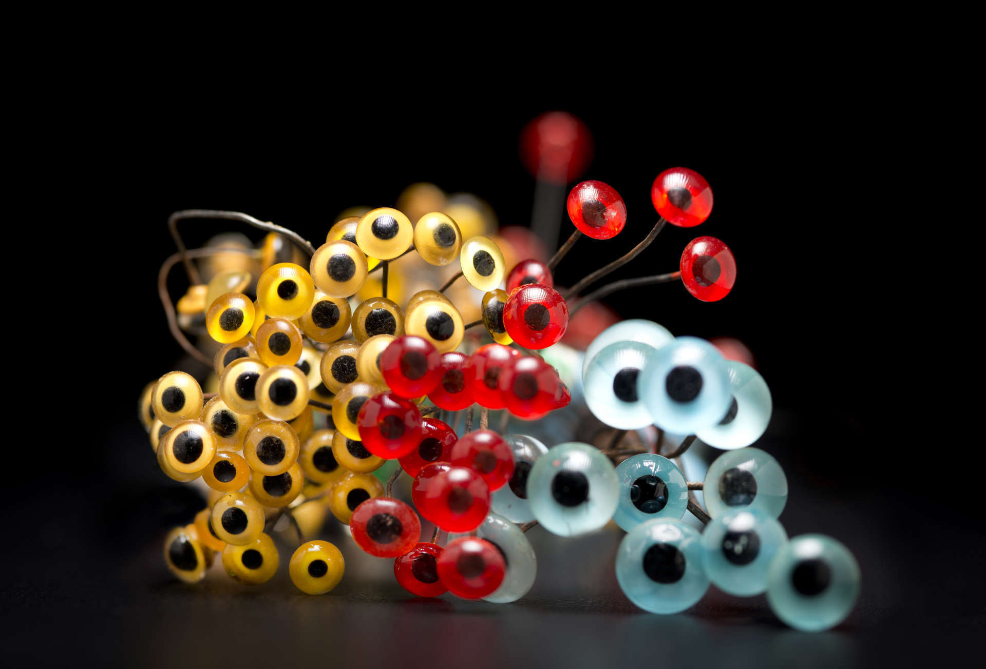 bunches of glass eyes from our taxidermy collection in bright colors of teal, red and yellow on a black background