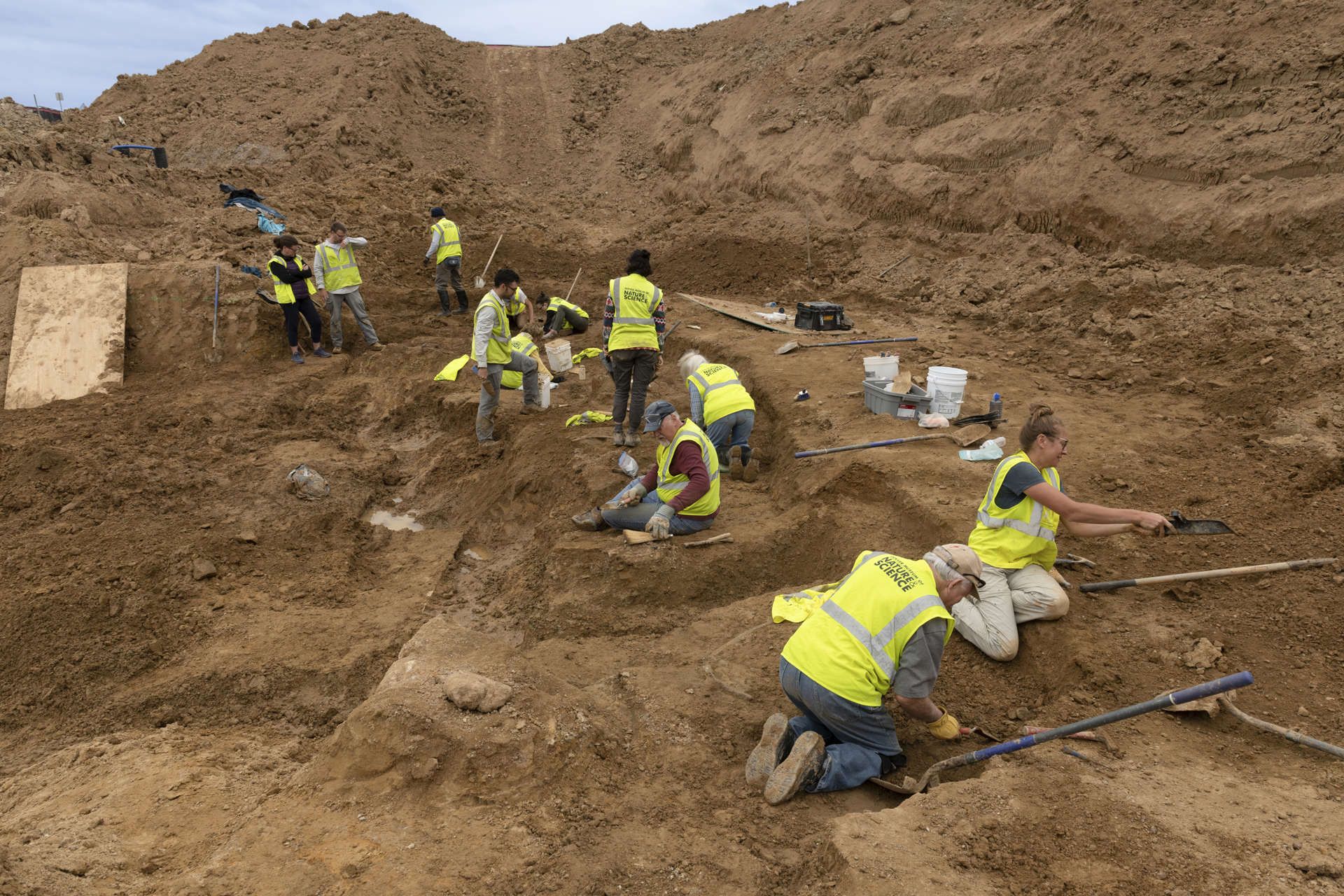 a wide view of a large excavated dirt area with a group of people working in it.