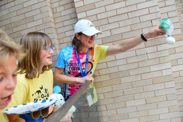 A teacher holds an egg over a landing, preparing an experiment observing the effects of gravity. 