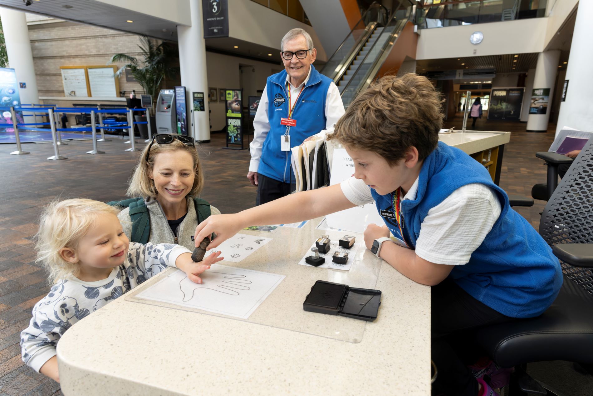 Giving out handstamps to enthusiastic Museum guests at the Info Desk. (Photo/ Rick Wicker)