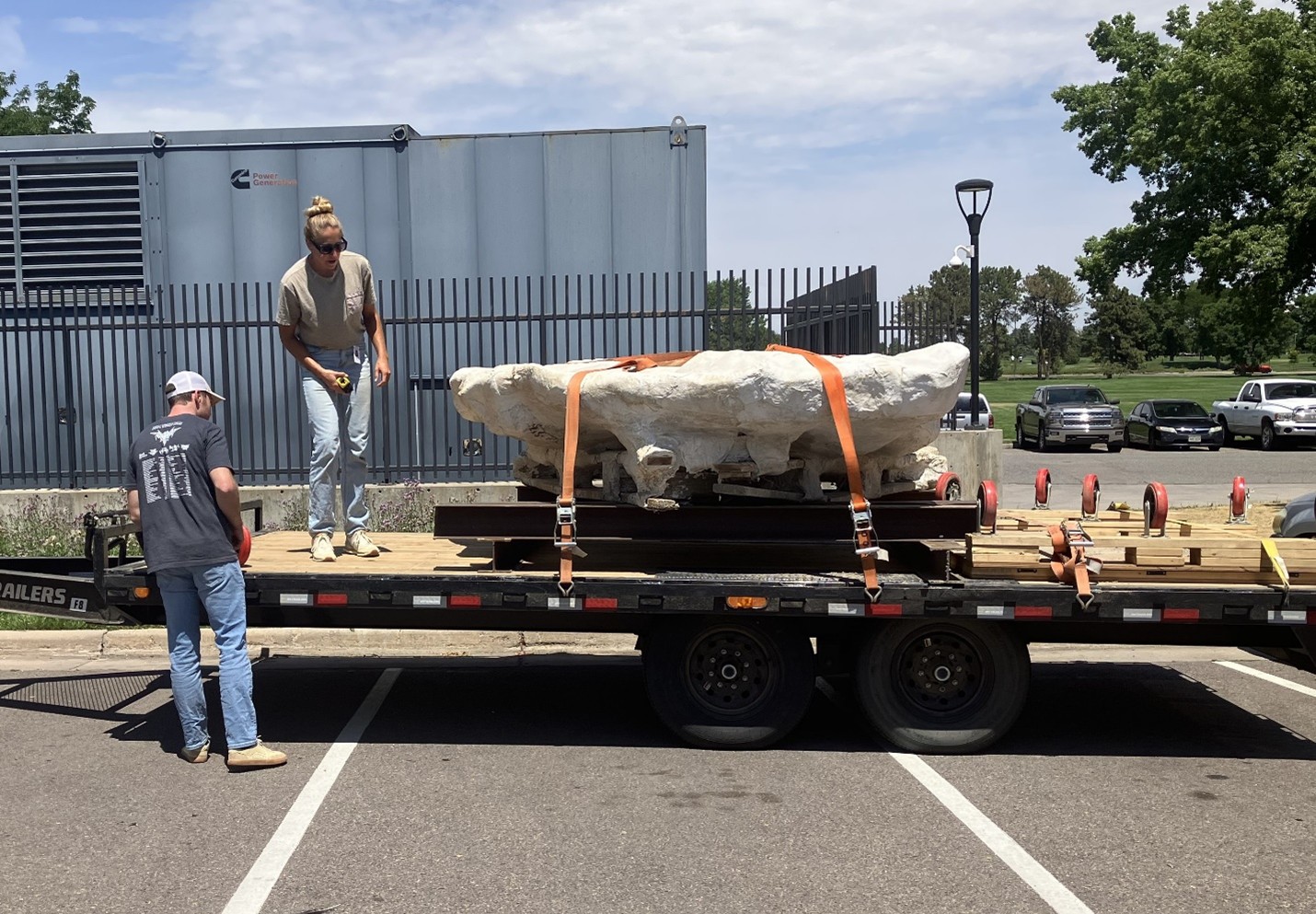 Fossil Preparators Salvador Bastien and Natalie Toth in the parking lot of the Museum discussing logistics for moving the fossil off the trailer.