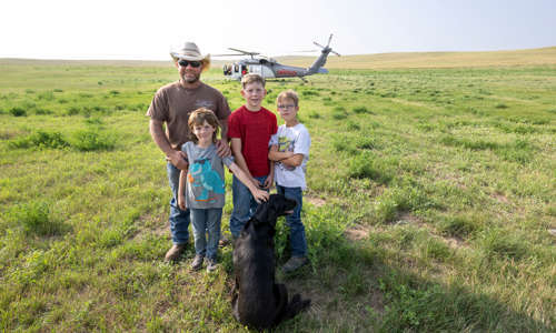The Fisher Family in a field in front of a helicopter