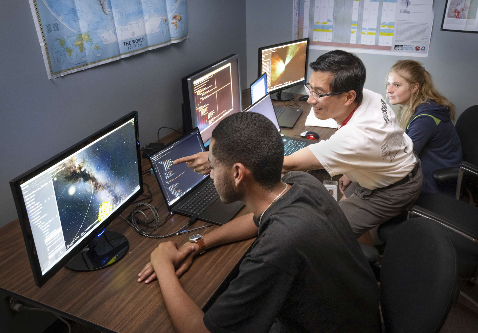 Two students sitting at computers with a mentor explaining what is on the screen