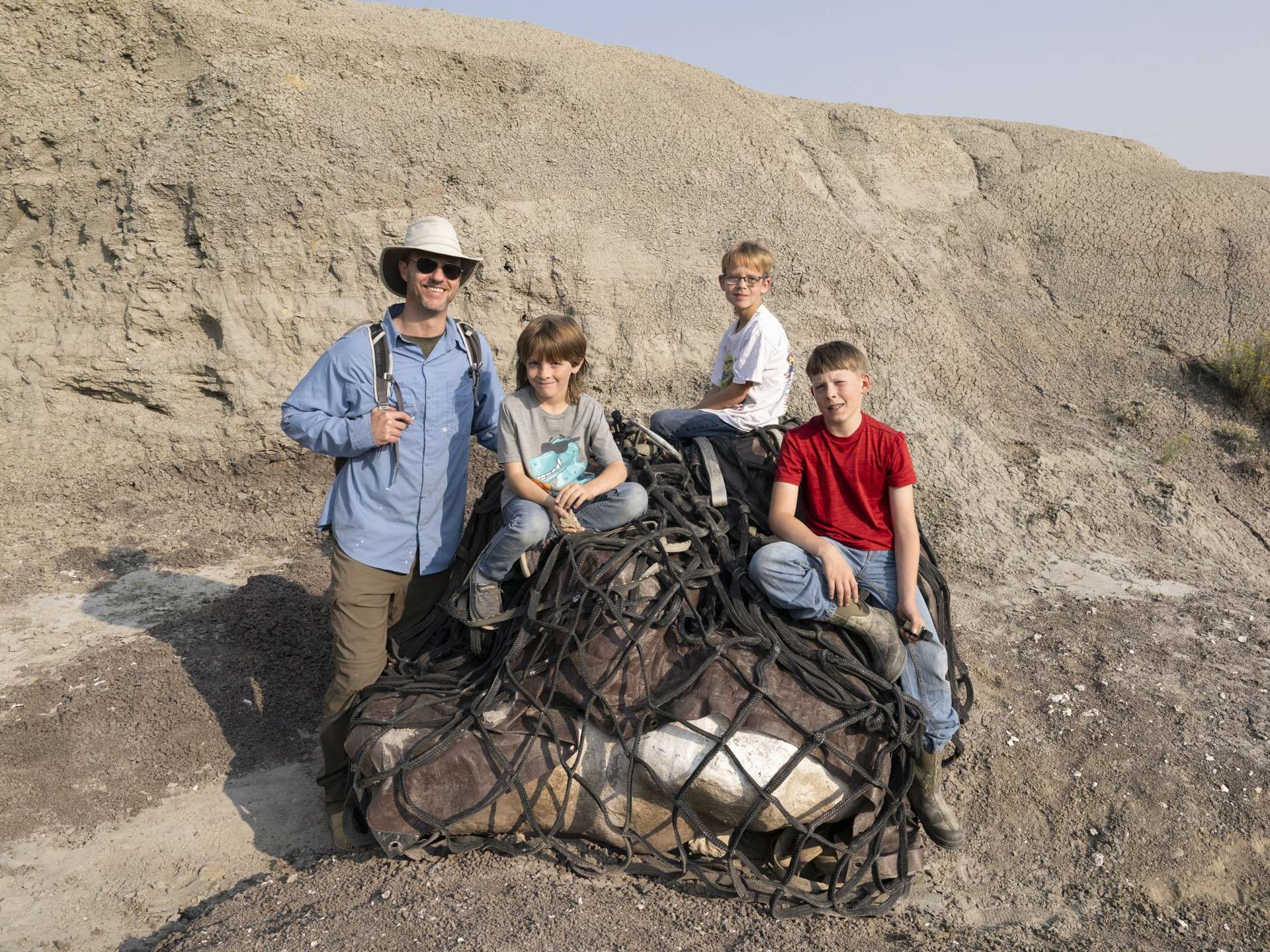 Dr. Tyler Lyson in the field with fossil finders Jessin Fisher, Kaiden Madsen, and Liam Fisher.