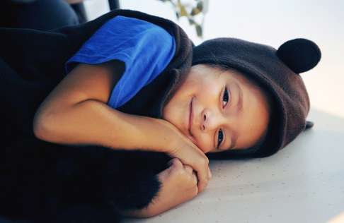 Young child laying on the floor, wearing a black bear costume
